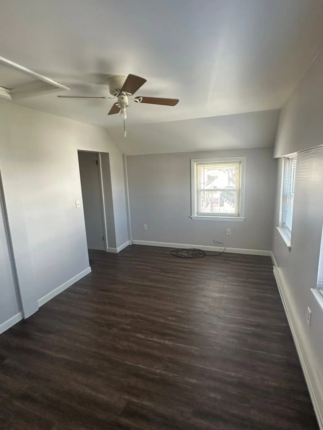 Completed dark wood-look LVP flooring with fresh light-gray paint and white trim, first room